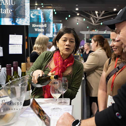 Woman serving wine to visitors at a wine show in Western Australia